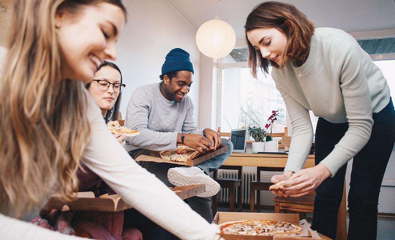 Ett gäng studenter som äter pizza tillsammans