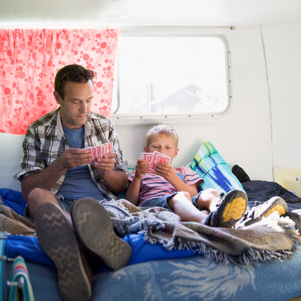 Pappa och son spelar kort i en husvagn